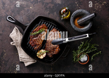 Grilled Black Angus Steak Striploin on frying cast iron Grill pan on dark background Stock Photo