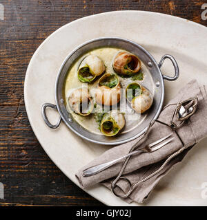 Bourgogne Escargot Snails with garlic herbs butter in aluminum pan on white plate Stock Photo
