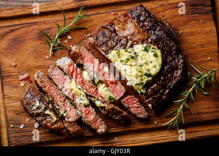 Sliced grilled Medium rare barbecue steak Ribeye with herb butter on cutting board close up Stock Photo