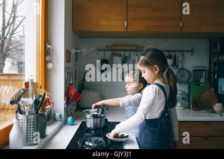 Girls melting chocolate in a kitchen Stock Photo