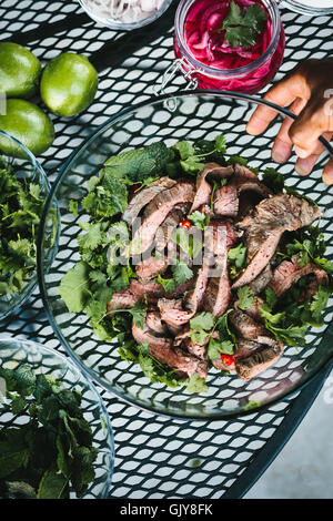 A large bowl of Thai Grilled Beef and Herb Salad is photographed from the top view. Stock Photo