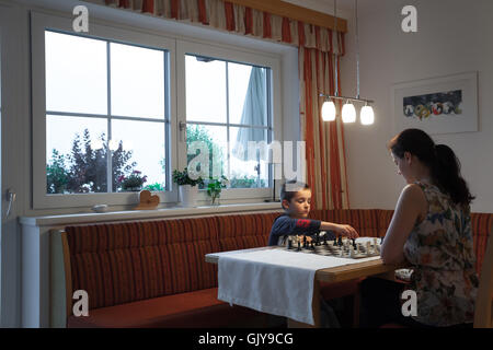 Young boy playing chess with his mother Stock Photo