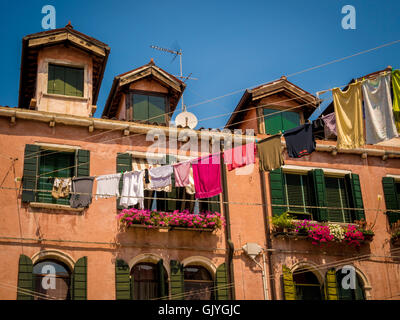 Traditional buildings with venetians blinds and window shutters, with laundry hanging from a washing-line. Venice, Italy. Stock Photo