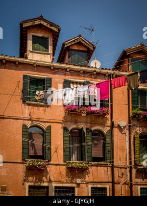 Traditional buildings with venetians blinds and window shutters, with laundry hanging from a washing-line. Venice, Italy. Stock Photo