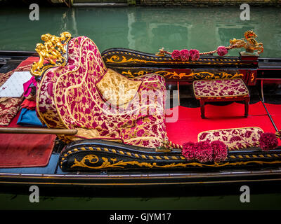 Ornate upholstered seats in a moored gondola. Venice, Italy. Stock Photo