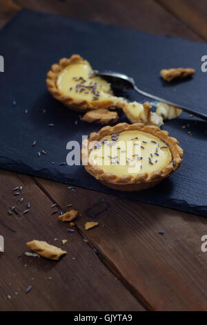 Lemon and lavender mini tarts on dark wooden table and slate board. Natural light, shallow depth of field. Stock Photo