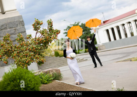 bride and groom with orange umbrellas Stock Photo