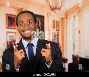 Handsome man wearing business suit smiling and pointing both index fingers to camera, lobbby background Stock Photo