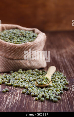 Close up the green mung beans in burlap sack on wooden board Stock Photo