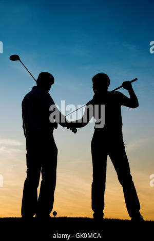 elderly couple playing golf in the sunset Stock Photo