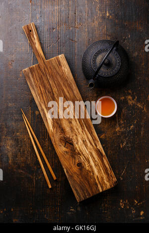 Wooden serving board for Sushi, chopsticks and green tea in teapot on wooden background Stock Photo