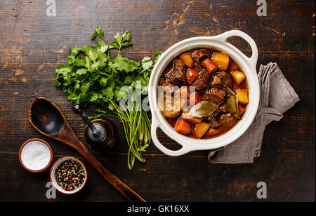 Beef meat stewed with potatoes, carrots and spices in ceramic pot Stock Photo