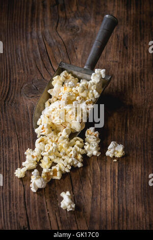 Prepared salted popcorn in old aluminum scoop over dark wooden background. With copy space Stock Photo