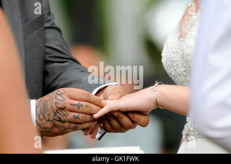 Groom placing wedding ring on the hand of his bride. Outdoor wedding. Stock Photo