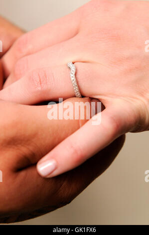 Groom placing wedding ring on the hand of his bride. Stock Photo