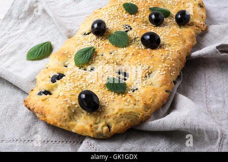 Italian bread focaccia with olive, garlic and herbs on the linen napkin. Homemade traditional Italian bread focaccia. Stock Photo