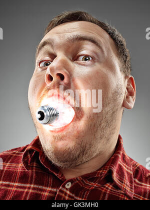 Caucasian man with bulb in his mouth on gray background Stock Photo