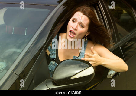 young woman sitting in car and screaming in anger Stock Photo