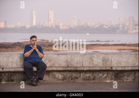 An Indian man prays as he sits on a bench in Mumbai, India  Credit: Euan Cherry Stock Photo