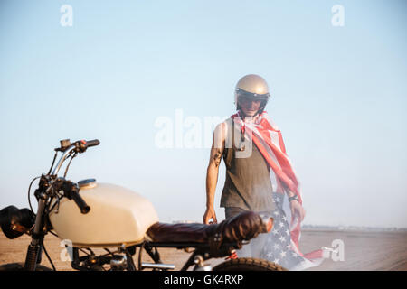 Close up of motorcycle with a man on the backgroud standing in desert Stock Photo