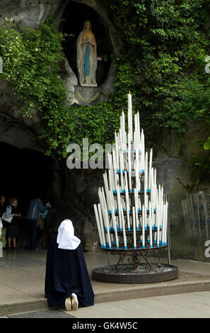 May 2009, Lourdes, France, France --- A nun prays in front of the statue of the Virgin Mary as she appeared to Bernadette Soubir Stock Photo