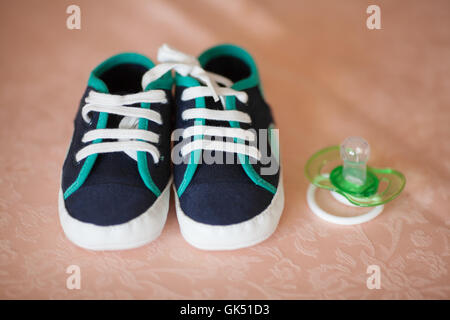Baby booties and dummy on a sofa Stock Photo