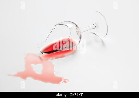 Broken Red Wine tasting glass with wine on a plain white background Stock Photo