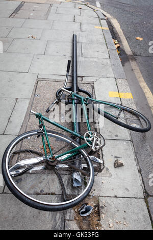 The remains of a vandalized bicycle are still locked to a post Stock Photo