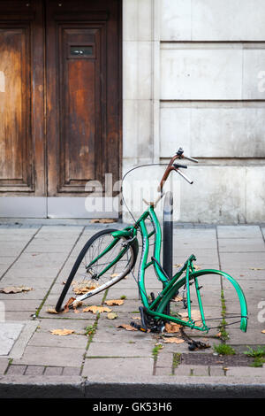 The remains of a vandalized bicycle are still locked to a post Stock Photo