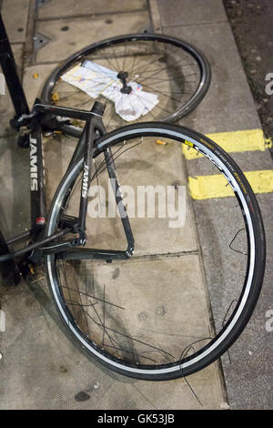 A frame and two wheel locked to a lamp post are all that remains of a bicycle which has been stripped of its parts Stock Photo