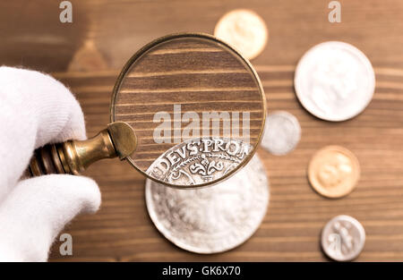 Examining old silver coin Stock Photo