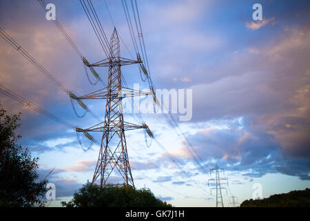 Electricity pylons and power lines ar dusk with a moody environmental sky Stock Photo