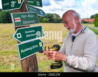 Walking trail keeper Horst Jaekel affixes a walking path sign in the Muskauer Faltenbogen geopark near the small village of Pusack an der Neisse, Germany, 11 August 2016. To keep the routes in good condition, trail keepers check them regularly. PHOTO: PATRICK PLEUL/DPA Stock Photo