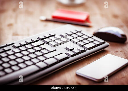 Desktop in the office, computer keyboard, pc mouse and mobile phone on the wooden table, work place Stock Photo