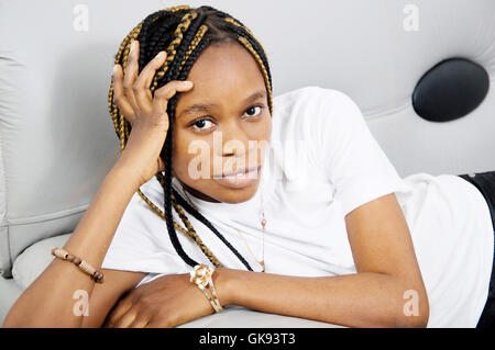 This young woman lying on the couch hand supporting her head , looks at the camera for a beautiful photo Stock Photo