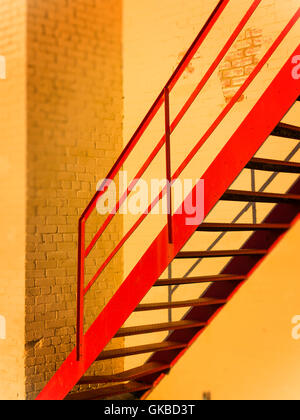 Red stairwell against yellow painted bricks during "Golden Hour", Virginia Beach, VA Stock Photo