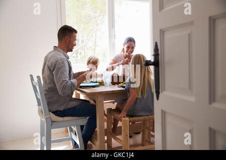 Family eating at table in sunlit room Stock Photo