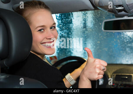 young woman driving a car in car wash Stock Photo