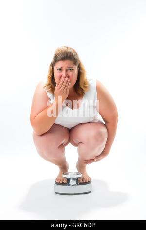 thickness young woman crouching on scale Stock Photo