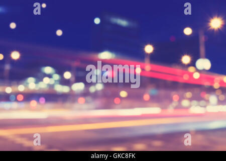 Vintage toned blurred street lights at night, urban abstract background. Stock Photo