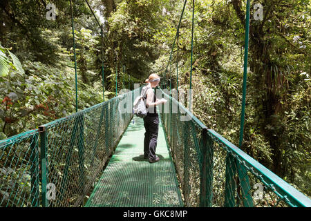 Woman tourist  walking on a canopy bridge, Monteverde cloud forest reserve, Monteverde, Costa Rica, Central America Stock Photo