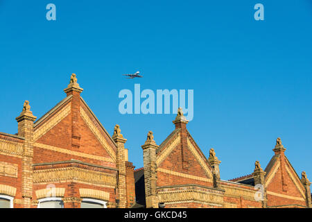 A plane coming into land set against the Lion statues on the gables and gateposts of the 'Lion Houses' in Barnes, SW13. Stock Photo