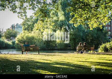 People relaxing in the summer sun next to Barnes Pond in central London Stock Photo