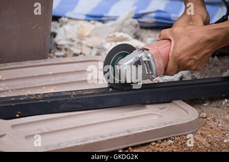 worker cutting steel or aluminum plate with electrical wheel grinder Stock Photo