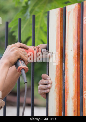 carpenter hands using electric drill on fence wood Stock Photo