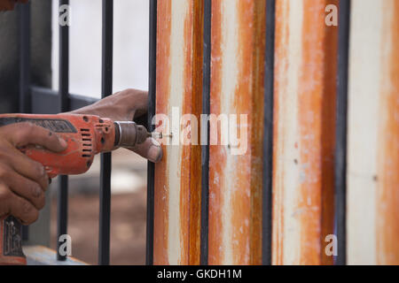 carpenter hands using electric drill on fence wood Stock Photo