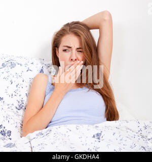 young attractive woman lies in bed and yawning in the morning Stock Photo