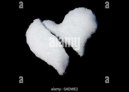 Broken heart made of snow isolated on black Stock Photo
