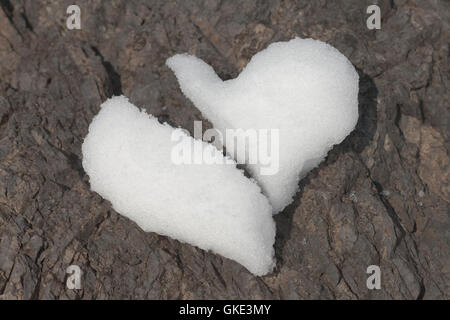 Broken heart made of snow on rock Stock Photo
