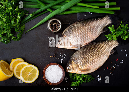 Two fresh raw crucian on a wooden background with herbs. Top view Stock Photo